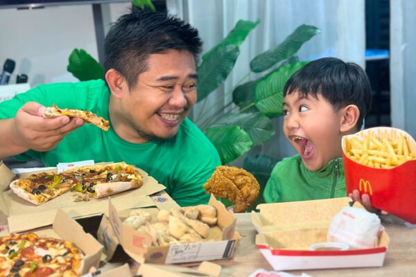 Louie, a dad in his early 40s, sitting his son Luis eating pizza & chicken — a real moment of presence from the LifeSharesTogether family